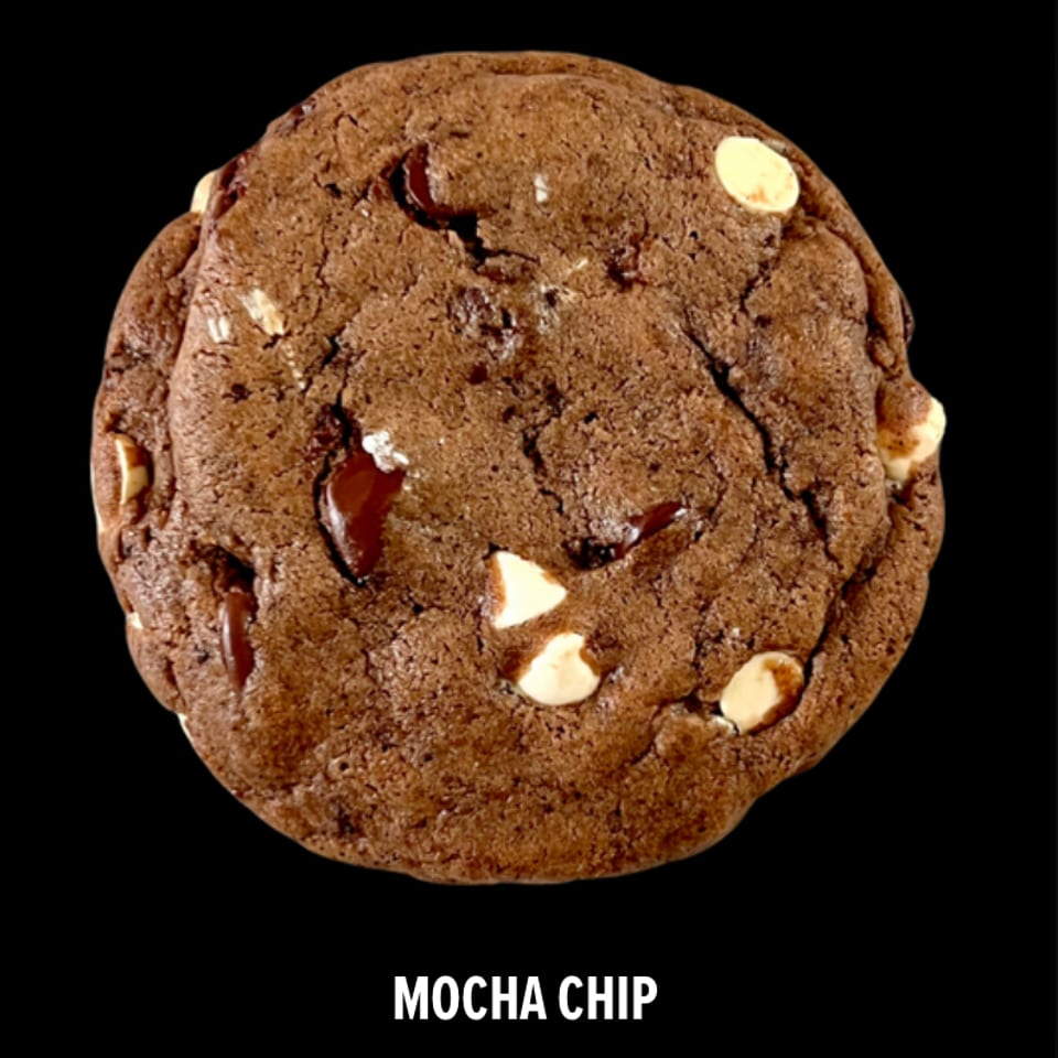 Close-up of a mocha chip cookie with dark chocolate and white chocolate chips on a black background.